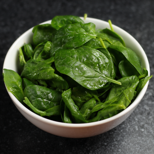 Fresh spinach leaves in a white bowl, commonly used in high protein pasta recipes | kaynmaytkal.com