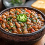 Bowl of spicy pinto bean chili topped with herbs and sliced jalapeño | kaynmaytkal.com